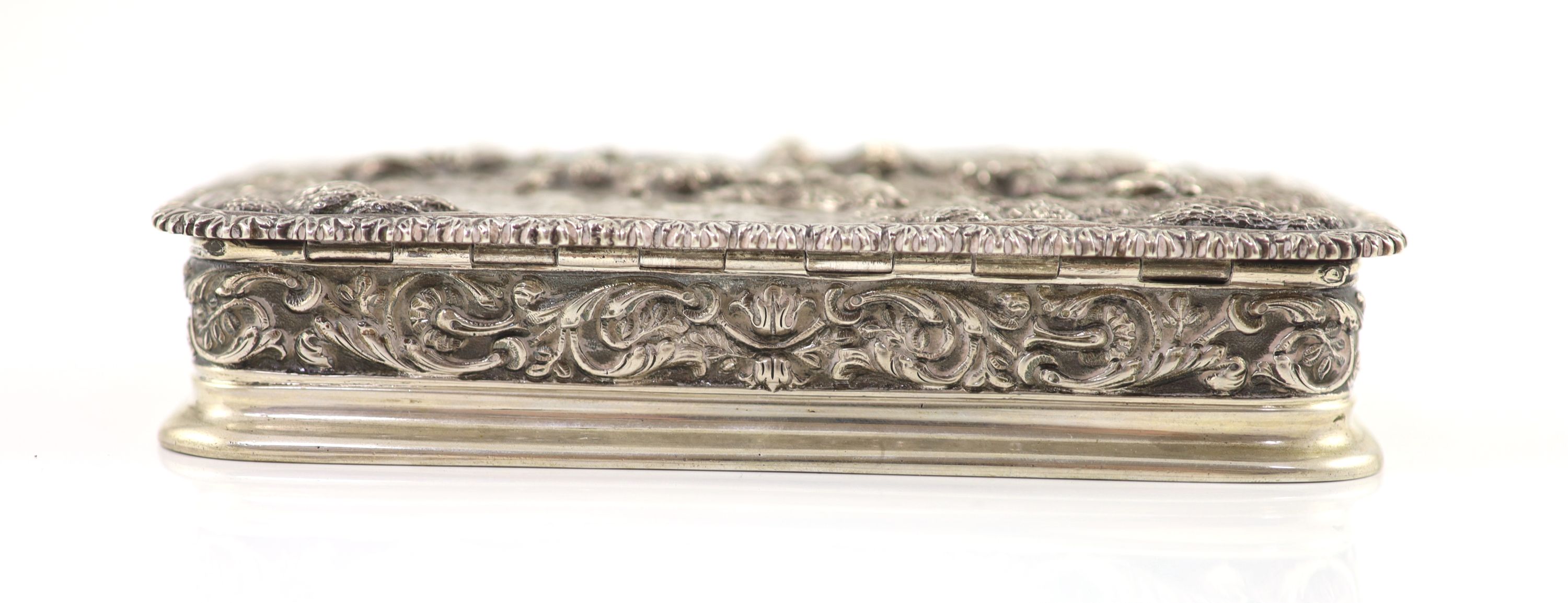 A 20th century Portuguese 833 standard silver rectangular box and cover, the lid cast and chased in high relief with travellers approaching a town,